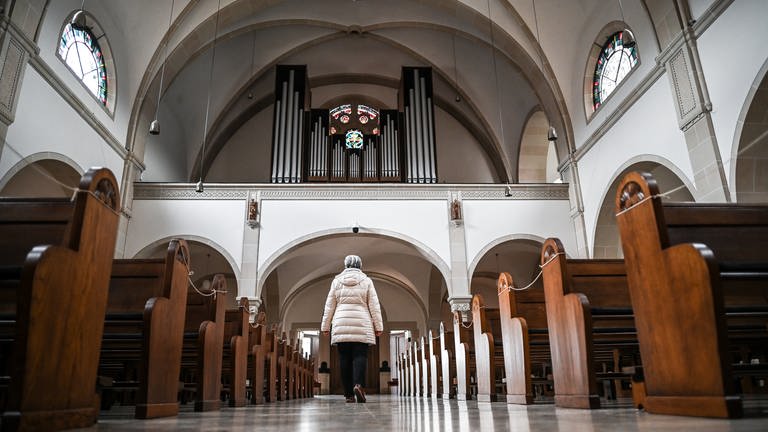 Symbolbild: Eine Frau verlässt eine Kirche, deren Bänke leer sind. Die Evangelische Landeskirche in Baden hat im vergangenen Jahr mehr als 31.000 Mitglieder verloren. 