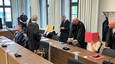 Die drei Verurteilten im Prozess zum Doppelmord in Altenstadt umringt von ihren Anwälten. Das Ehepaar bekam jeweils lebenslänglich. Der Mitangeklagte wurde zu einer mehrjährigen Haftstrafe verurteilt. (Foto: SWR, Markus Bayha)